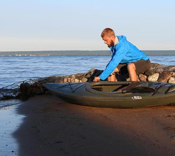 Young man adjusts his kayak before going in the water.