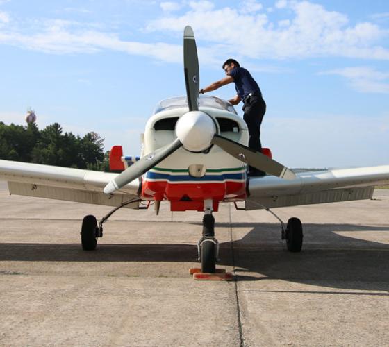 Aviation student standing on side of plane for inspection 