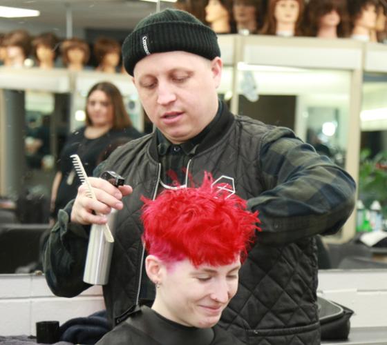 Workshop instructor teaching students about short hair techniques on student in salon