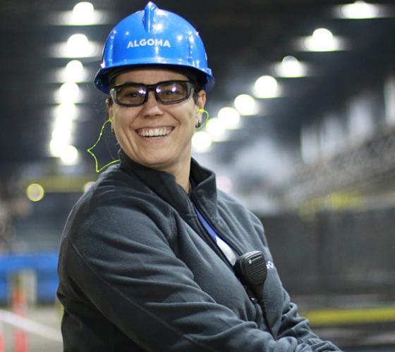 Skilled Trades alumni wearing hard hat smiling on-site at Algoma Steel.
