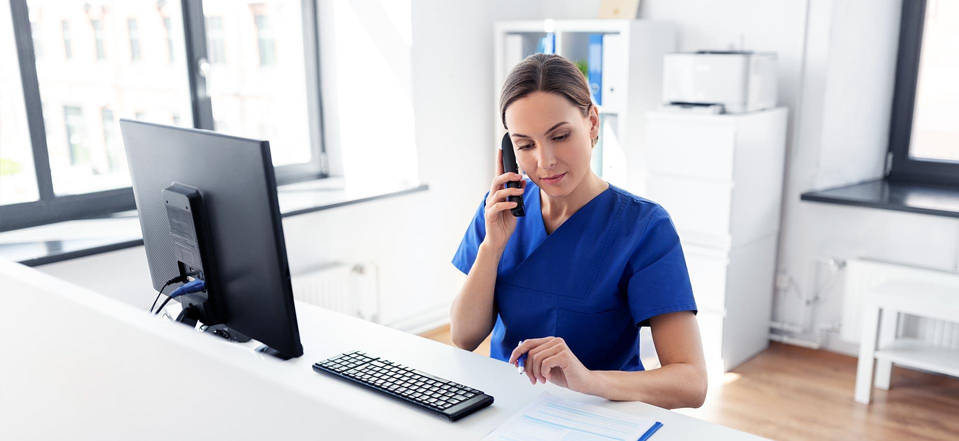 Female health office worker answers phone at her desk.