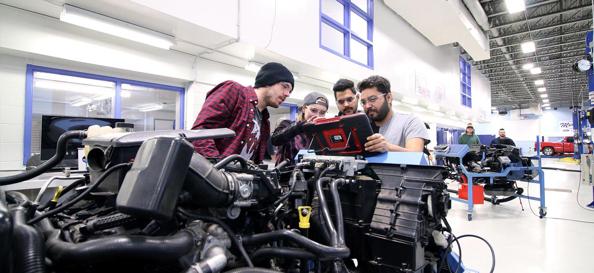 A group of male Motive Power Technician - Advanced Repair students run diagnostics on a car engine. 