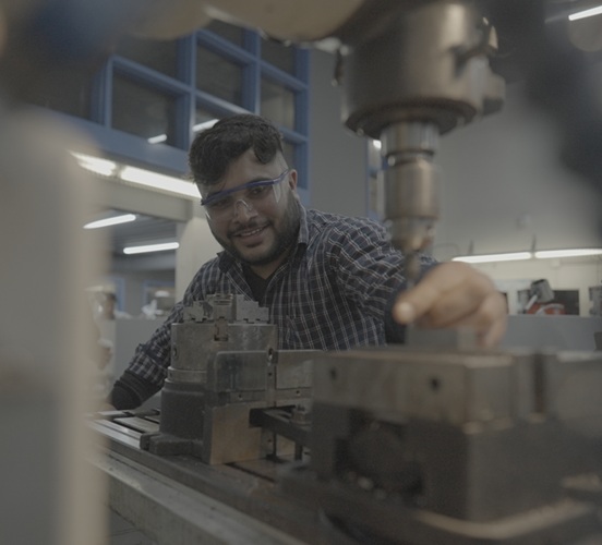 Skilled trades student working in the machine shop with equipment