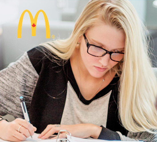 Business student looking down while working at desk with McDonald's logo to side