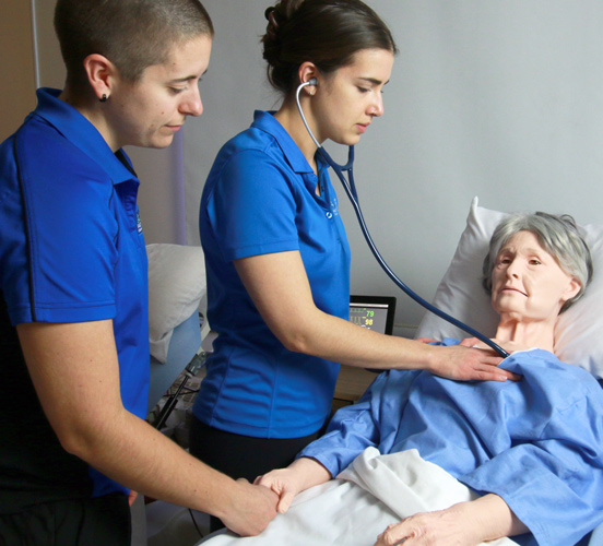 nursing students checking on manikin patient in sim lab