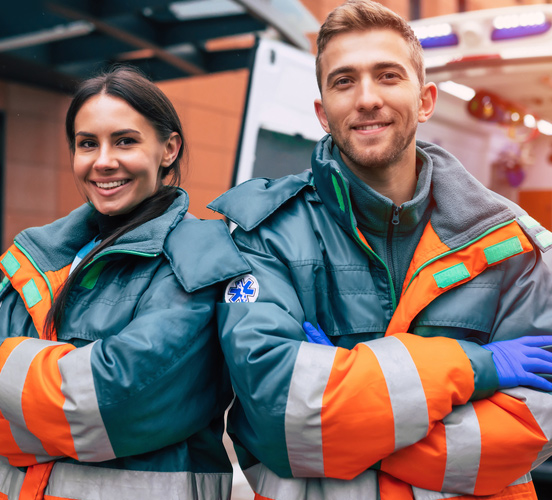 Two paramedics standing together in front of ambulance with back doors open