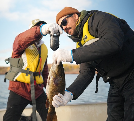 SONE students at Field Camp on a boat in the water looking at fish caught