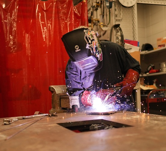Welding student working on project in lab with sparks