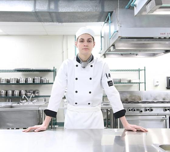 A male Sault College Culinary student poses for a photo in one of the culinary kitchens.
