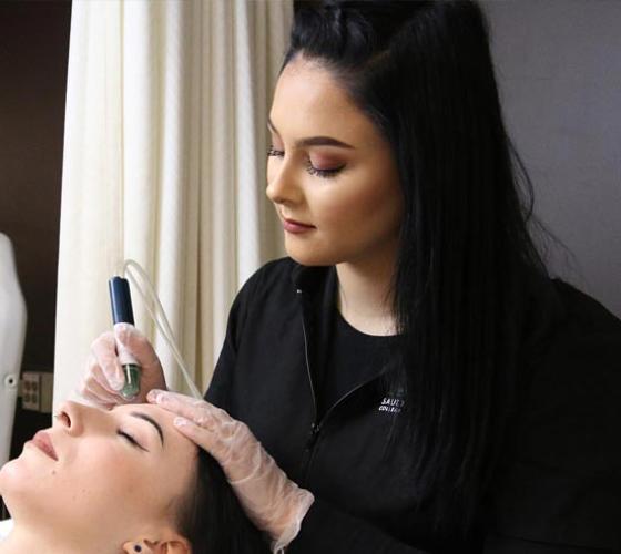 One female Esthetician student applies a skin treatment to another student in the Sault College salon spa.