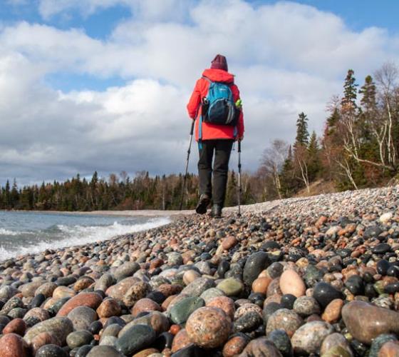 Woman hiking on rocky shore.