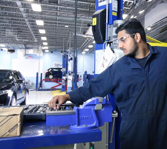 A male Motive Power Fundamentals - Automotive Repair student works on an engine.