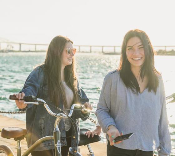 Two young women smiling on the boardwalk.