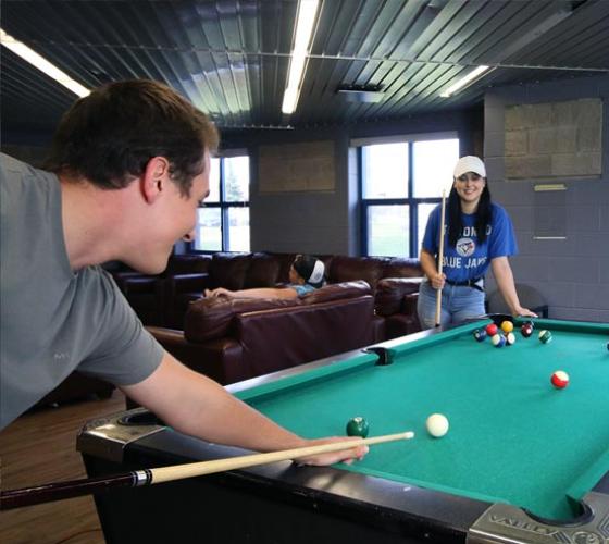 Two students playing pool on campus.