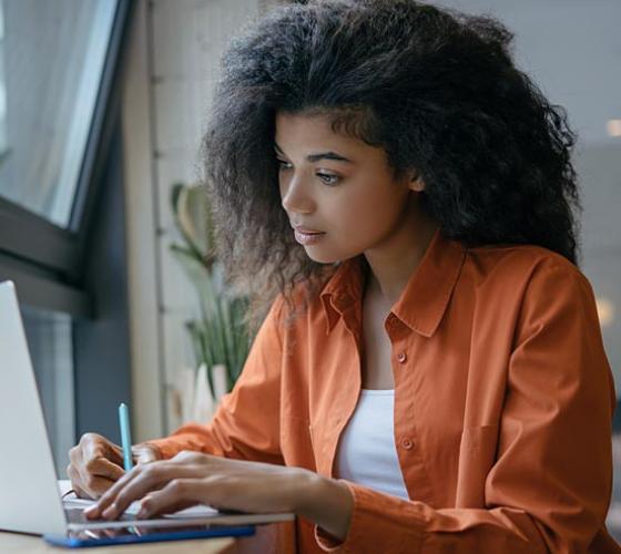 Young woman on a computer near a window.