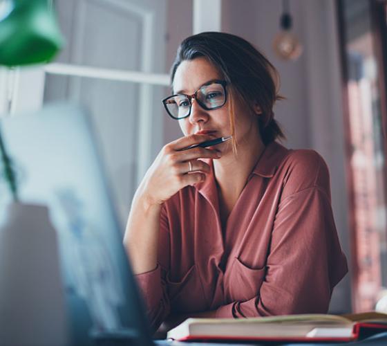 Female student thinking at her computer.