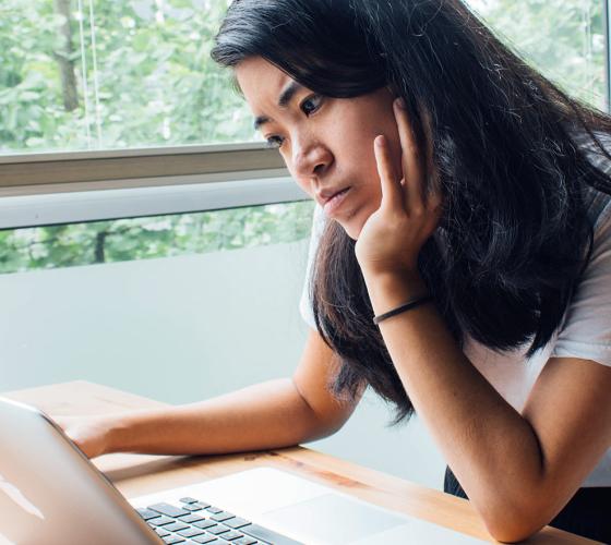 Female student thinking while on computer.