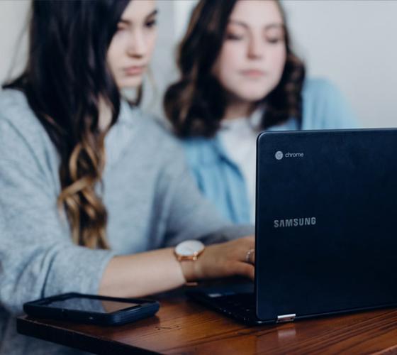 Two female students at a computer.