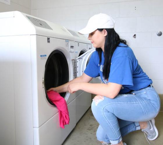 Girl putting clothes into washing machine