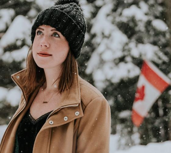 Female Canadian student in front of flag.