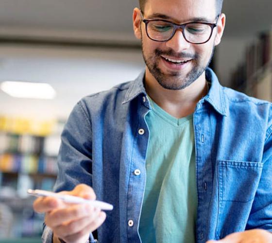 Male looking at book with pen in hand