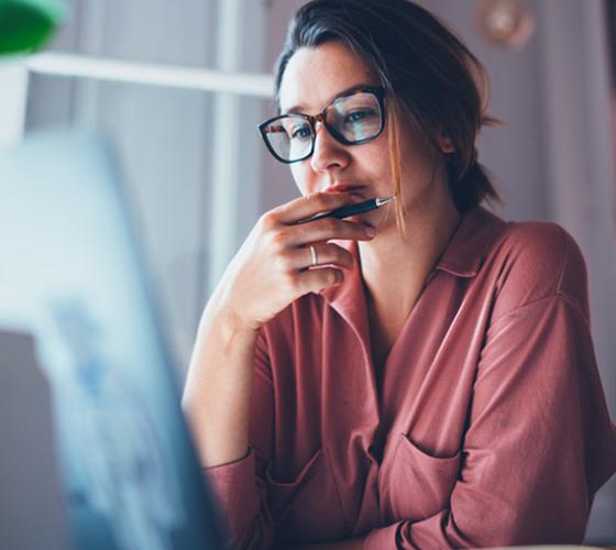 Female student thinking at her computer.