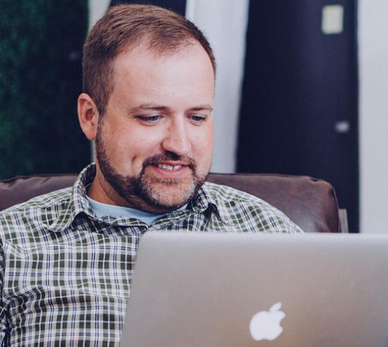 Male adult smiling on computer.