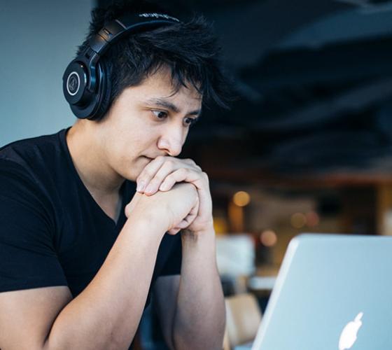 Male student at computer thinking.