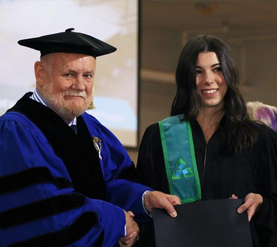 Female graduate receives her diploma from Ron Common.