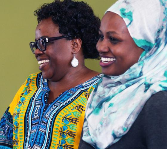 Two female students laughing in colourful clothing.