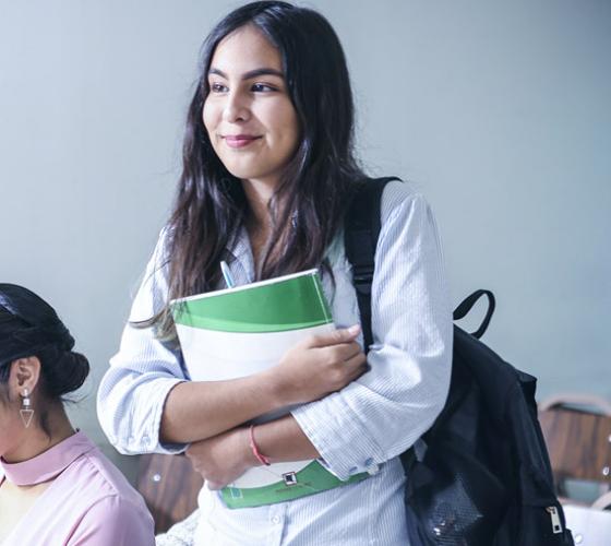 Female high school student smiling and standing in class.