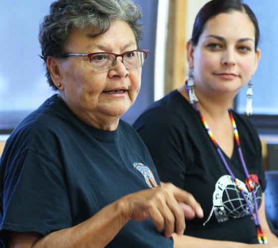 indigenous elder speaking beside younger indigenous person