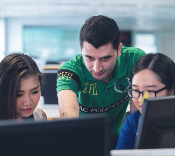 Three international students reading a computer.