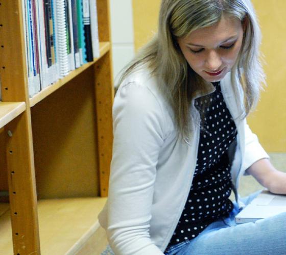 Female student sitting down reading in library.