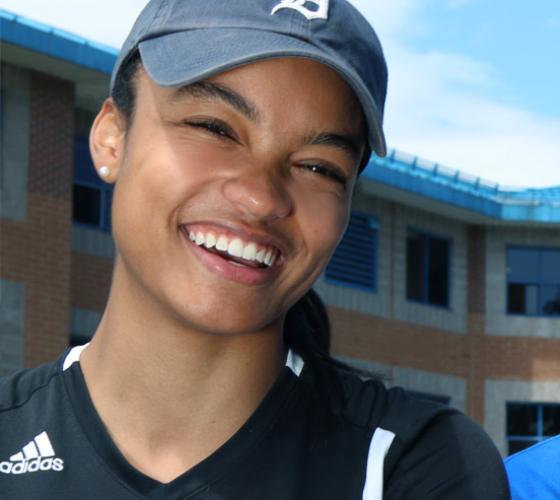 Female student smiling in front of residence.