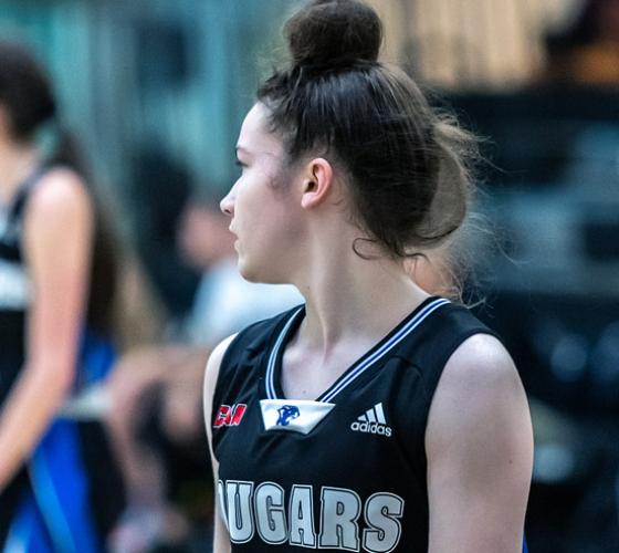 Female cougar basketball player observes the game.