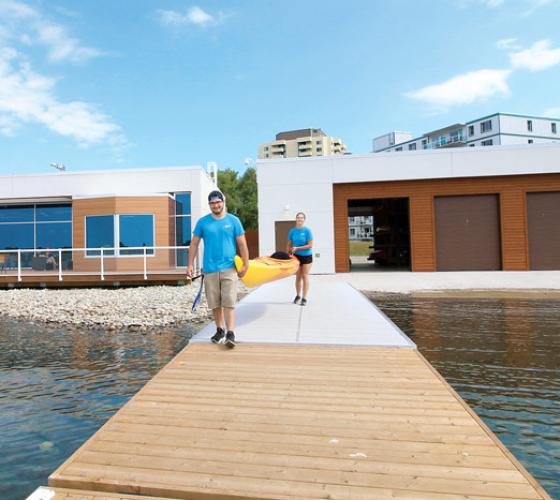 Students walking on a dock carrying a kayak