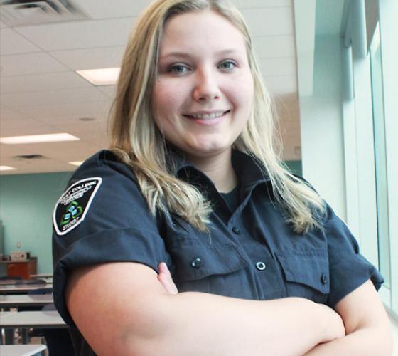 student standing by windows dressed in security uniform