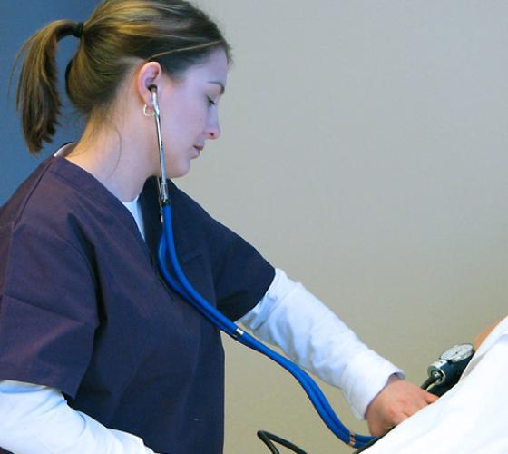 nurse with stethoscope measuring blood pressure on a patient