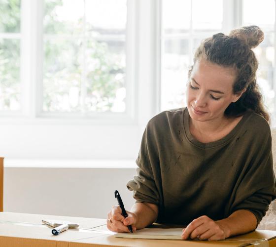 female in a home making notes on a moving box