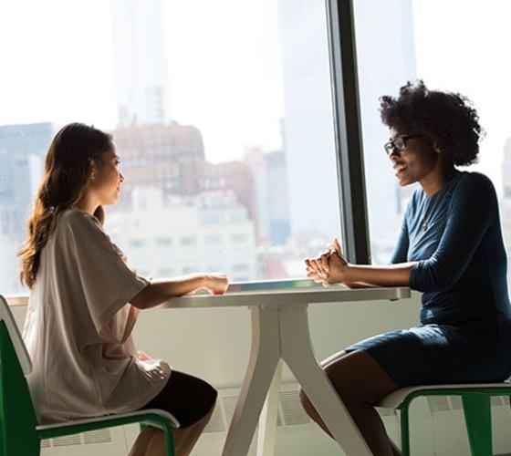 Two women sitting at desk discussing employment