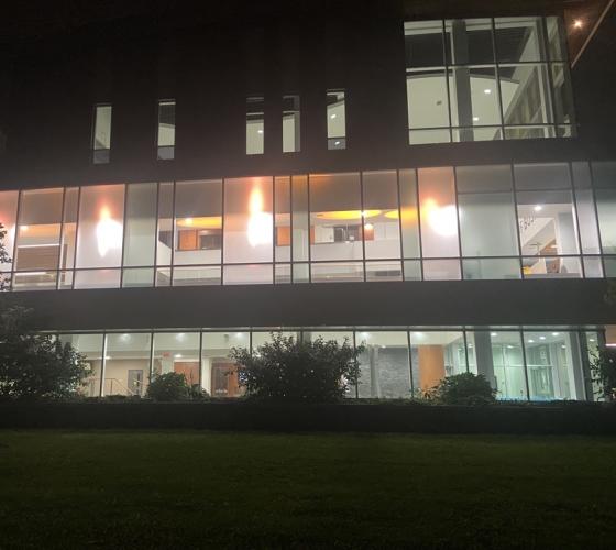 Photo of M-Wing building corridor where you can see orange lighting through the large glass windows.