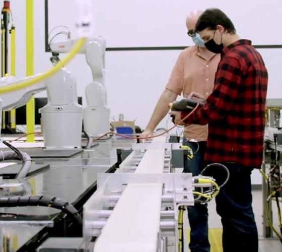 Student and instructor in mechatronics lab with multiple robot arms