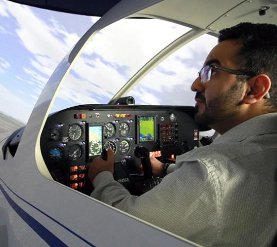 aviation student shown using flight simulator with flight training of a sky on large screen ahead