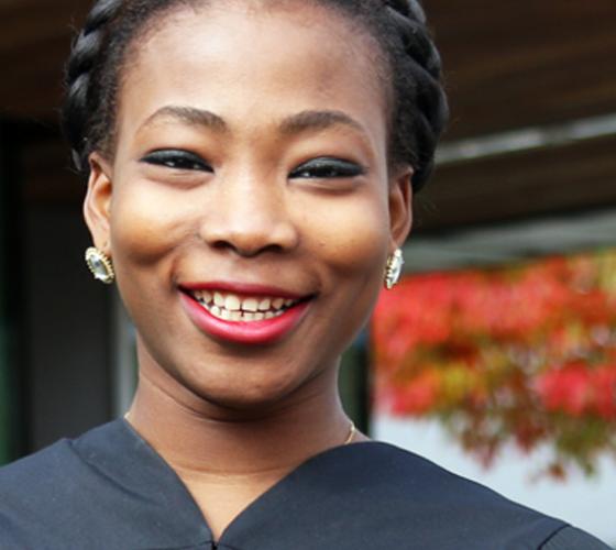 graduate wearing robe smiling looking at camera