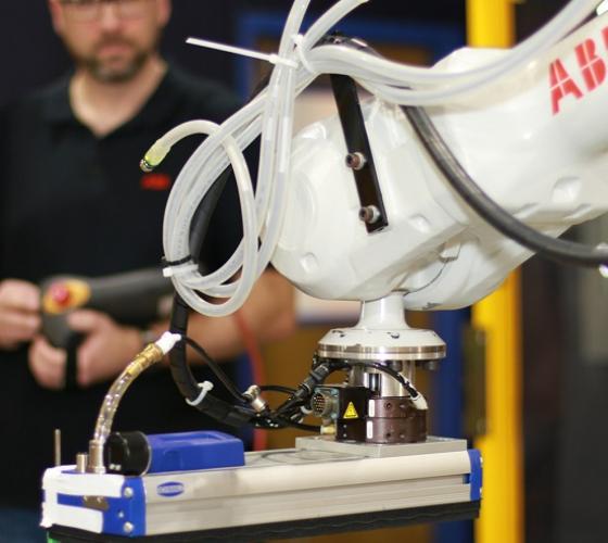 Engineering instructor in background controlling robotics equipment