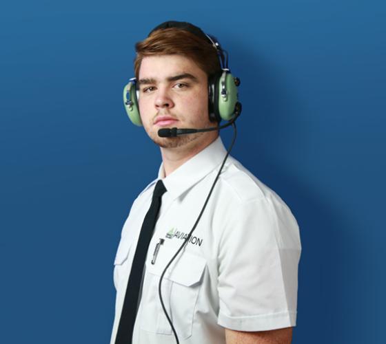 Aviation student in uniform and with headset looking at camera