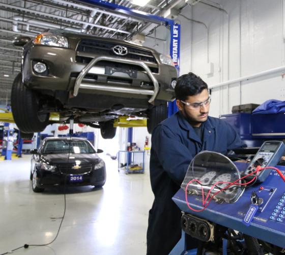 Automotive student in coverall working in the Motive Power Centre