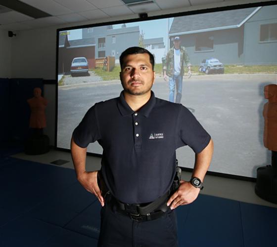 Policing student in uniform looking at camera in simulation training lab with screen in background