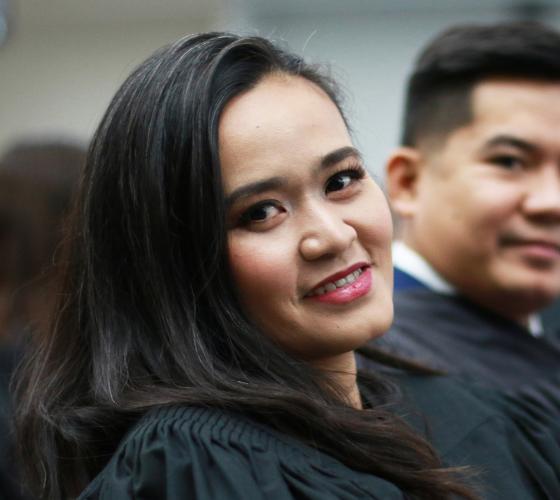 Student in graduation robe sitting at convocation and looking at camera